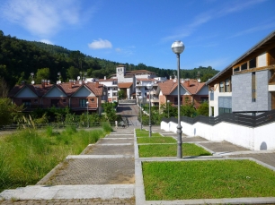 Una calle de Axpe, con las casas del barrio y las laderas verdes que enmarcan Busturia.