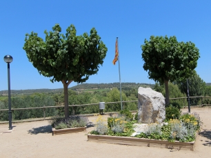 Dos árboles enmarcan una vista del paisaje rural de El Pla del Penedès desde un espacio público del municipio.