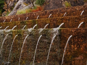 La Fuente de los Cien Caños, adosada a la pared caliza de la sierra: el agua emerge por numerosas salidas y hace visible el vínculo entre roca y manantial.