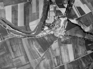 Fotografía aérea histórica de Barañáin, tomada entre 1927 y 1934: las parcelas de cultivo y el curso sinuoso del río muestran la escala rural del paisaje.