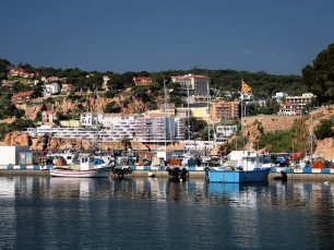 El puerto de Sant Feliu de Guíxols, con embarcaciones junto al frente urbano y los sectores rocosos del litoral.