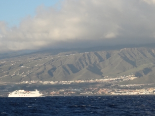 Adeje visto desde el mar, con las laderas surcadas por la erosión detrás de la franja costera construida.