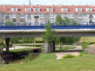 El puente sobre el curso de agua en Bertamiráns, con el paseo y las viviendas al fondo, resume el encuentro entre el valle y la ciudad reciente.