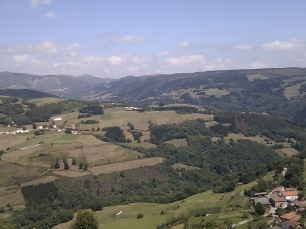 Una vista de Allande entre laderas, prados y sierras. El relieve que aparece en el horizonte separa las aguas entre las cuencas del Navia y del Narcea.
