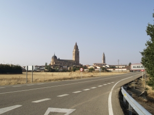 Alaejos aparece al fondo de la carretera, con las torres de sus iglesias elevándose sobre el paisaje llano.
