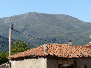 Tejados de Rascafría ante una ladera de la sierra de Guadarrama: el pueblo y la montaña comparten el horizonte.