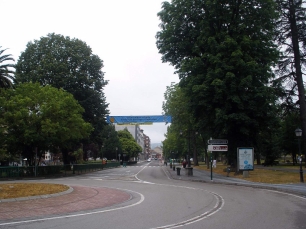 Una avenida arbolada de Grado muestra el tejido urbano de la villa y el paisaje que la rodea.