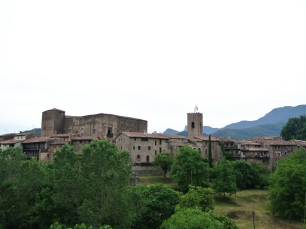 Vista exterior de Santa Pau, con el núcleo urbano en primer plano y las elevaciones del entorno al fondo.