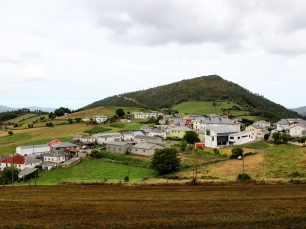 Villayón se extiende bajo una loma, con el caserío en primer plano y las sierras como telón del concejo.