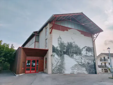 En una fachada de Zaratamo, una pintura de gran formato reproduce una escena de calle. La imagen acompaña el recorrido por los barrios habitados del municipio.