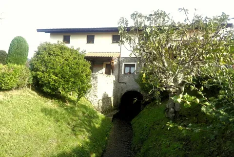 El agua pasa junto al molino de Errotabarri; el canal muestra cómo la corriente se integra en el conjunto.