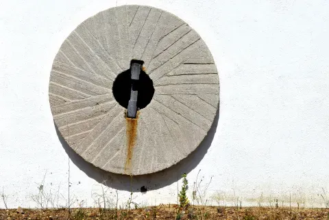 Una antigua muela de molino expuesta como elemento ornamental en Belvís de la Jara. Su presencia acompaña la memoria de la molienda documentada en el municipio.