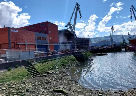 Instalaciones de Murueta en Altzaga, con el borde construido y una escalera hacia el agua visibles junto a las naves.