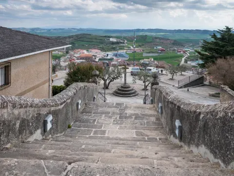 La escalinata bajo la basílica de Mendía desciende hacia el caserío y el paisaje agrícola de Arróniz.