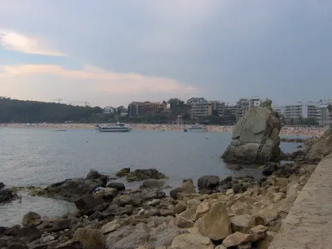 Rocas en primer término y playa al fondo en Lloret de Mar: dos superficies distintas que ayudan a reconocer el contraste entre piedra y arena del litoral.