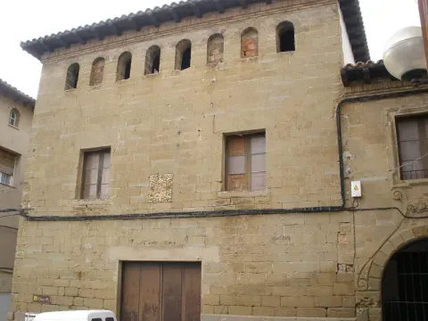 Fachada de una casa de Ayerbe, con vanos y galería de arcos en la parte superior. La imagen acerca el recorrido al tejido construido de la villa.