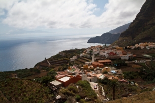Vista de Agulo desde las laderas: el casco y las parcelas ocupan el borde entre las alturas y el océano.