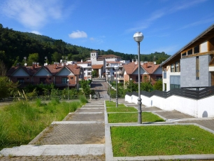 Una calle de Axpe, con las casas del barrio y las laderas verdes que enmarcan Busturia.