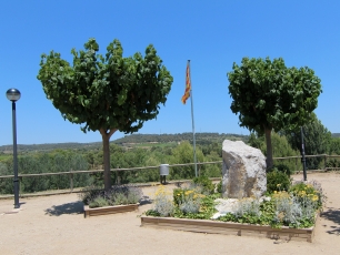 Dos árboles enmarcan una vista del paisaje rural de El Pla del Penedès desde un espacio público del municipio.