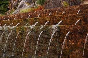La Fuente de los Cien Caños, adosada a la pared caliza de la sierra: el agua emerge por numerosas salidas y hace visible el vínculo entre roca y manantial.
