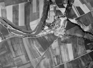 Fotografía aérea histórica de Barañáin, tomada entre 1927 y 1934: las parcelas de cultivo y el curso sinuoso del río muestran la escala rural del paisaje.