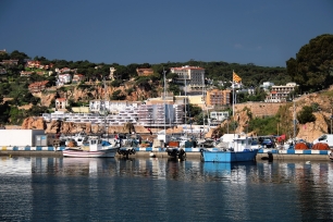 El puerto de Sant Feliu de Guíxols, con embarcaciones junto al frente urbano y los sectores rocosos del litoral.