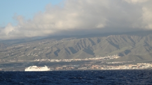 Adeje visto desde el mar, con las laderas surcadas por la erosión detrás de la franja costera construida.