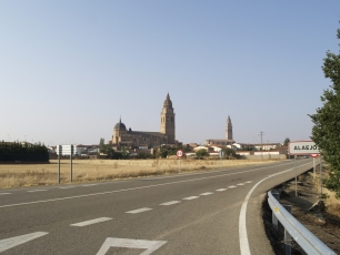Alaejos aparece al fondo de la carretera, con las torres de sus iglesias elevándose sobre el paisaje llano.