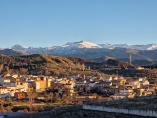 Beas de Granada entre lomas, con Sierra Nevada al fondo, visto desde la carretera GR-3107. En su término nace el río Beas, afluente del Darro.