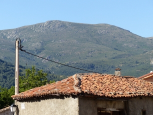 Tejados de Rascafría ante una ladera de la sierra de Guadarrama: el pueblo y la montaña comparten el horizonte.