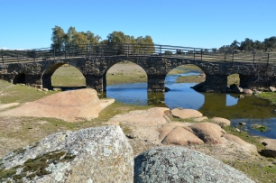 El puente sobre el río Salor, en el entorno de Torreorgaz. La roca visible junto al cauce forma parte del paisaje de la penillanura.