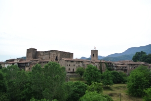 Vista exterior de Santa Pau, con el núcleo urbano en primer plano y las elevaciones del entorno al fondo.